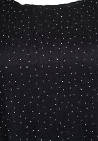 Un tissu noir avec un motif de grille texturé et de petits points blancs en relief dispersés sur toute la surface.