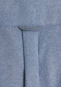 Hellblauer Denim-Stoff mit einer subtilen Textur, mit einem gefalteten Design oben und einem sauber verarbeiteten Rand.