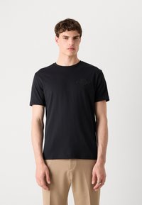 Tricou negru cu mânecă scurtă, cu decolteu rotund și un design subtil embossat pe pieptul stâng. Fabricat dintr-un material neted, cu o croială confortabilă.