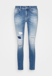 Úzké džíny ve světle modrém denimu s desgignem poškození. Obsahují zesvětlené části, několik děr a klasický pětivreckový design.