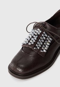 Dark brown textured leather dress shoe with lace and decorative silver bead embellishments on the upper front.