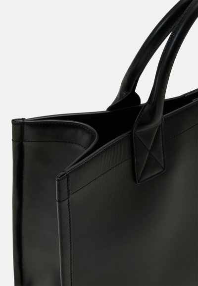 Sac fourre-tout en cuir noir avec une texture lisse, doté de deux poignées robustes et d'une couture précise le long des bords. Design à ouverture supérieure.