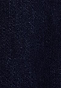 Zbliżenie ciemnoniebieskiego denimu ukazujące szczegółową diagonalną fakturę tkaniny oraz subtelne białe kropki.