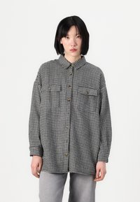 Black and white houndstooth shirt, featuring long sleeves, a button-up front, two chest pockets, and a classic pointed collar.