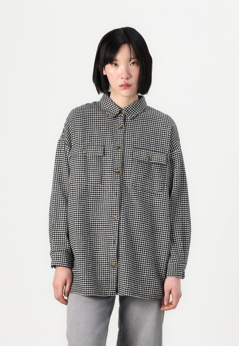 Black and white houndstooth shirt, featuring long sleeves, a button-up front, two chest pockets, and a classic pointed collar.