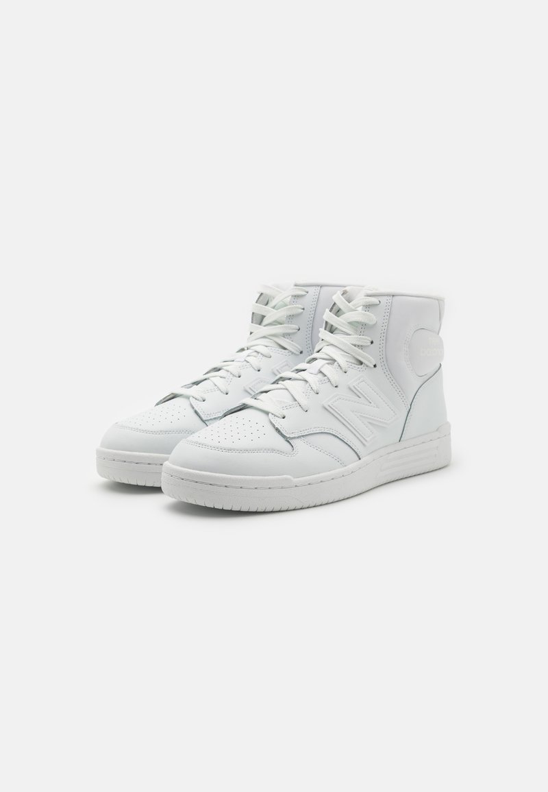 Sneaker alte in pelle bianca con dettagli perforati, lacci piatti e una suola in gomma bianca testurizzata. Presentano un sottile accento con logo.