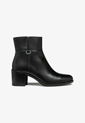 Black leather ankle boot with a smooth finish, a zip closure, and a textured block heel. Features a small metal loop accent on the back.