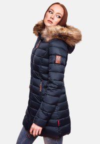 Navy puffer jacket with faux fur hood trim, quilted design, side pockets, and logo patch on sleeve. Features a zipper closure and accent details.