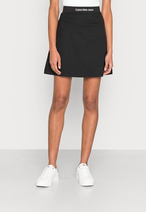 Černá bavlněná sukně skater s přiléhavým pasem s bílým logem "Calvin Klein Jeans". Délka nad kolena s rozšířeným střihem.