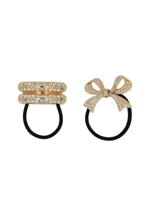 Deux élastiques à cheveux : l'un est doré métallisé avec des strass clairs, en forme de barre ; l'autre est un nœud doré avec des strass, tous deux sur des bandes élastiques noires.