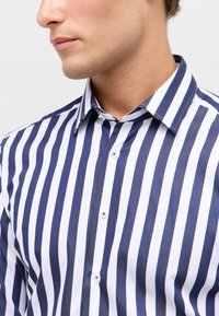 Marineblauwe en witte gestreepte shirt gemaakt van een gladde stof, met een klassieke kraag, knoopsluitingen en gelijkmatig verdeelde verticale strepen.