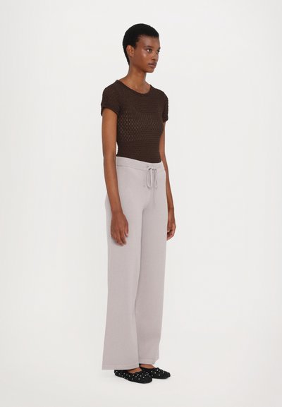 Brown knit short-sleeve top paired with light gray wide-leg pants featuring a drawstring waist. Black shoes with white polka dots.