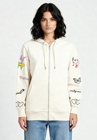 Krem hoodica na patent s printom u boji, uključujući cvijeće i srca, s opuštenim krojem i prednjim džepovima.
