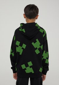 Felpa nera con cappuccio caratterizzata da grandi forme pixelate verdi, con cappuccio regolabile e polsini a costine. Tessuto morbido con vestibilità casual.