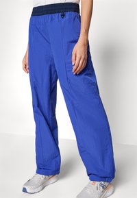 Calças cargo leves azuis com cintura elástica e cordão, apresentando bolsos laterais e um corte solto, feitas de tecido durável.