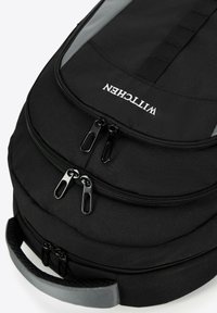 Sac à dos en tissu noir avec deux compartiments zippés, une poignée grise et un logo sur le dessus. Présente une surface texturée et une forme ergonomique.