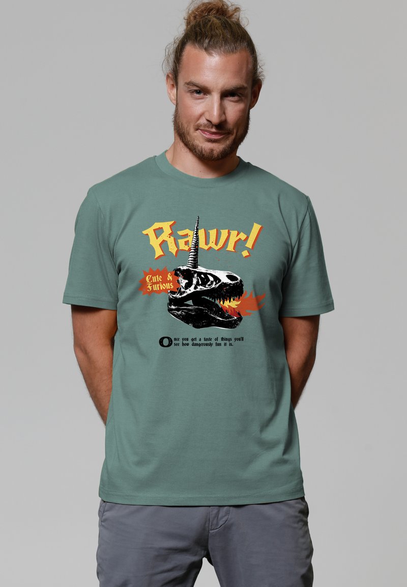 Grünes Baumwoll-T-Shirt mit einem Motiv eines Dinosaurierschädels mit einem Einhornhorn, orangefarbenem Text "Rawr!" und schwarzen Flammenakzenten.