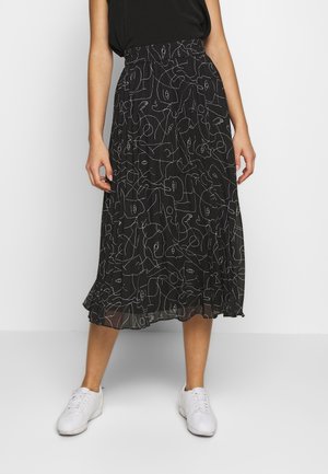 Sort midi-nederdel med hvid abstrakt linjekunst af et ansigt, båret med sort top og hvide sneakers, vist på en person stående mod en ensfarvet baggrund.