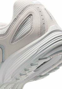 Ljusgrå träningsskor med ovandel i mesh och mjuka läderdetaljer. Har en texturerad sula och unika kurviga designelement.