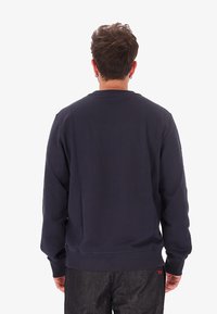 Felpa blu navy con maniche lunghe e collo rotondo. Materiale in cotone liscio, polsini e orlo a coste, design semplice senza stampe.