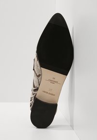 Semelle d'une chaussure à bout pointu avec talon et bout noirs, semelle intermédiaire beige marquée "Weekend", taille 37, et dessus texturé à motif serpent.