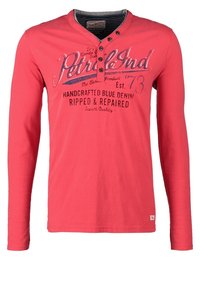 Rotes Langarmshirt aus Baumwolle mit einem Henley-Kragen mit Knöpfen, bedrucktem Text und lockerer Passform. Akzente durch kontrastierende Nähte.