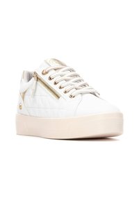 Sneaker bianco trapuntato con accenti dorati, cerniera laterale decorativa, lacci texturizzati e una suola spessa di colore crema.