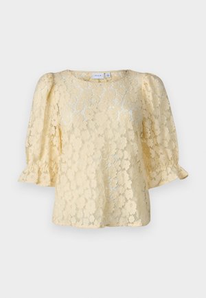 Top rendado em amarelo suave, com mangas curtas bufantes, decote redondo e padrões florais por toda a tecido.