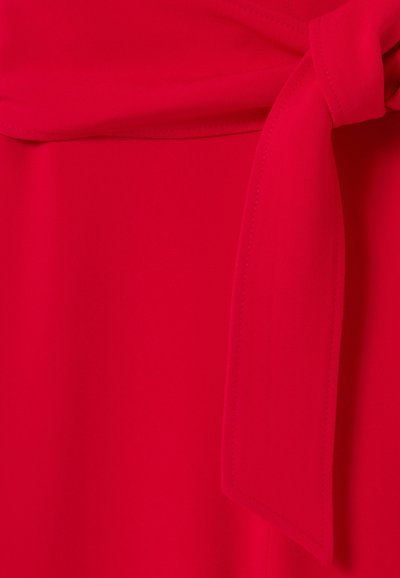 Tela roja con una textura suave que presenta un cinturón anudado en la cintura. El diseño incluye secciones dobladas y una costura cuidada.