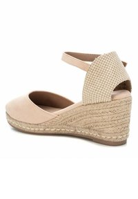 Sandalía de cuña beige de esparto con un suave acabado de ante en la parte superior, detalles de yute trenzado en la cuña y una correa en el tobillo para mayor soporte.