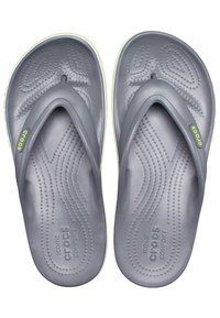 Paire de tongs Crocs grises avec motifs texturés sur la semelle et étiquettes de logo vertes sur les brides, vues de dessus.