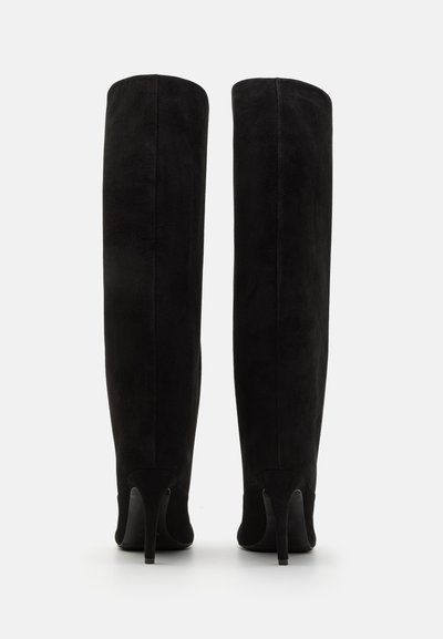 Līdz ceļiem melni zamša zābaki ar gludu tekstūru un smailiem stiletto papēžiem, kas piedāvā elegantu, cieši pieguļošu dizainu bez redzamiem piederumiem.