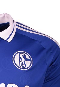 Maillot de sport bleu avec col blanc et trois bandes sur les épaules. Présente un logo d'équipe circulaire avec "S04" au centre.