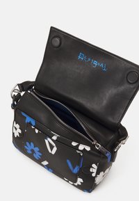 Mustalla nahkalaukulla, jossa on sinisiä ja valkoisia kukkakuoseja. Varustettu vetoketjullisella taskulla, napilla suljettavalla kannella ja sinisellä logolla sisällä.
