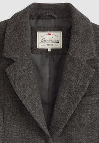 Blazer grigio a spina di pesce con colletto a lancia, foderato in raso e con etichetta interna che recita "Levi Strauss, Fondata nel 1873."