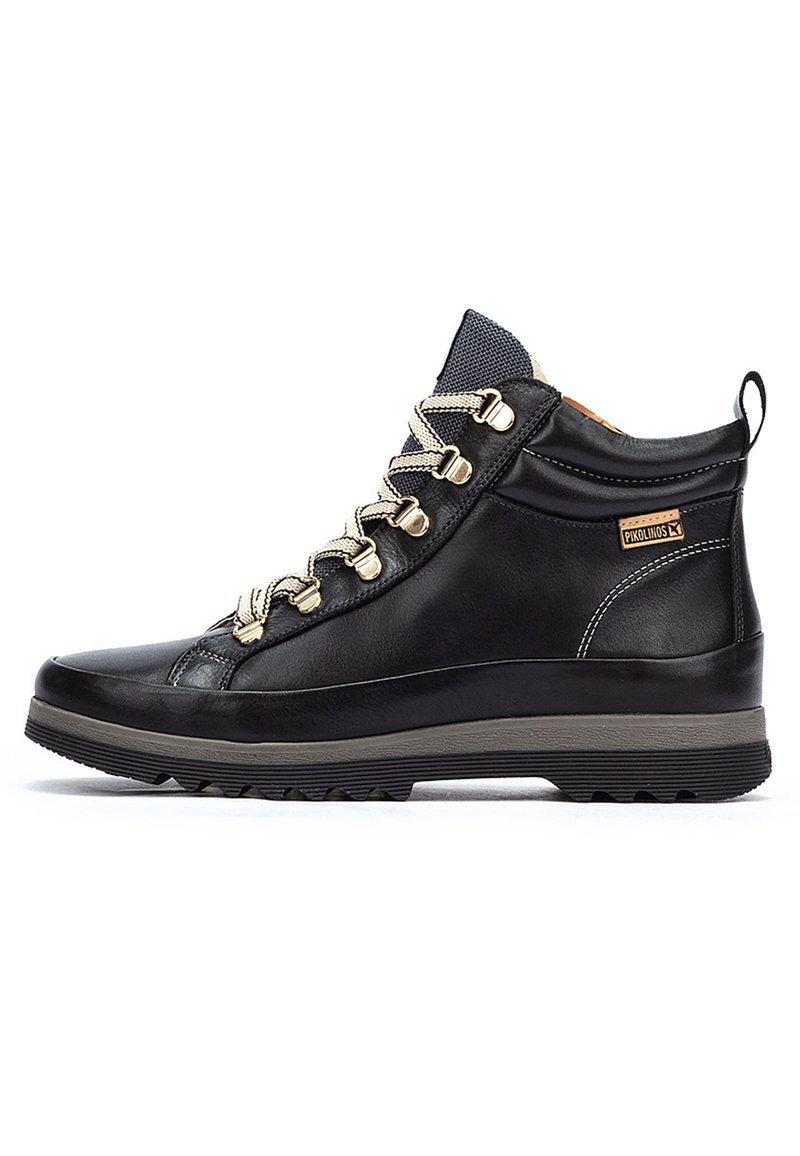 Bottines de randonnée en cuir noir avec un design montante, lacets beige, semelle en caoutchouc et œillets en métal. Présente un accent de logo sur le côté.