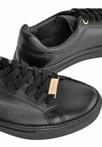 Czarne skórzane sneakersy o teksturowanym wykończeniu, z płaskimi sznurowadłami i złotym metalowym akcentem po boku. Posiadają gładki czubek i gumową podeszwę.