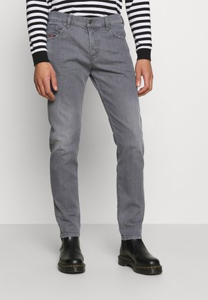 Harmaat farkut, joissa on istuva malli, viiden taskun tyyli ja hienovaraiset ompeleet, yhdistettynä mustiin nilkkureihin.