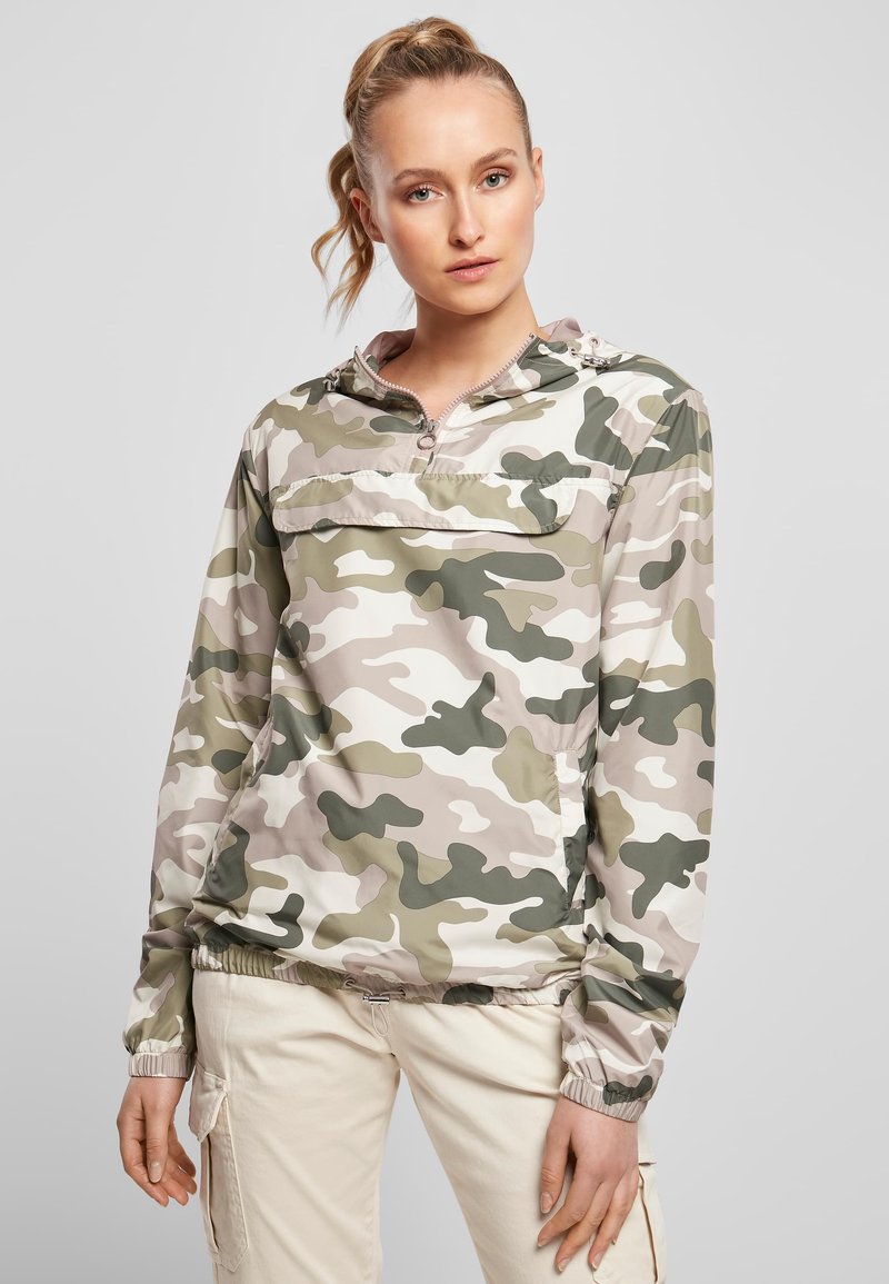 Kerge, beežide ja roheliste kamuflaažimustritega pullover, millel on poollukuga esikäis, elastsed varrukaservad ja esikott hoiustamiseks. Sile, veekindel materjal.