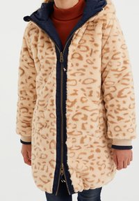 Beige Kunstpelzmantel mit Leopardenmuster, marinefarbenem Kragen und Reißverschluss, gerippten Bündchen und lockerer Passform. Zwei seitliche Taschen sind enthalten.