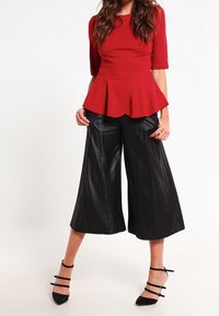 Rød peplum top med trekvartlange ærmer og sorte faux læder culottes. Afsluttet med sorte spidse stiletter med remme.