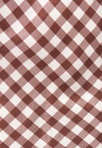 Puuvillakangas, jossa on punavalkoinen ruutukuvio, jossa ruudukossa vuorottelevat kiinteät ja kuvioidut neliöt.