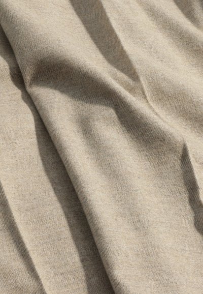 Beige tekstureret stof med synlige folder og et blødt udseende, der viser et let, vævet mønster med en lille glans.