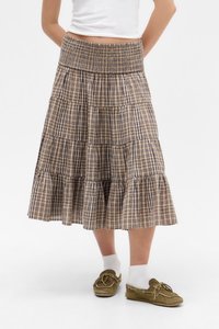 Hnědo-beige kostkovaná sukně s volánky a nařaseným pasem; měkká látka; do kolen; nošena s bílými ponožkami a zelenými botami.