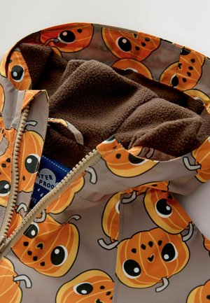 Veste imperméable avec motif de citrouilles orange, doublure en polaire marron, fermeture éclair et détails de design ludiques à l'intérieur.