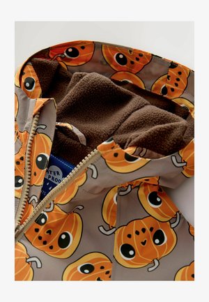 Veste imperméable avec motif de citrouilles orange, doublure en polaire marron, fermeture éclair et détails de design ludiques à l'intérieur.