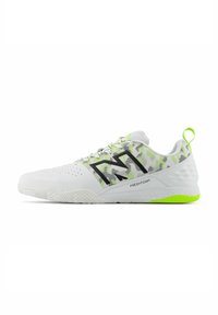 White athletic shoes with black accents and mesh detailing. Features a green outsole and reflective elements. Textured surface and laces.