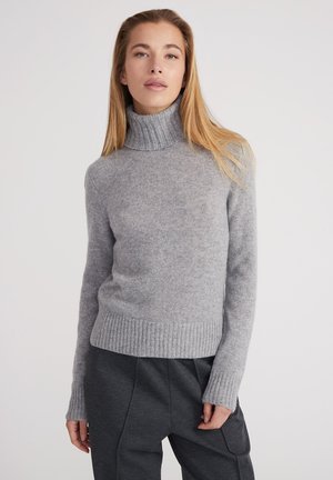 Pull à col roulé gris en tissu doux, doté de poignets et d'un ourlet côtelés, d'une coupe ajustée et d'une texture légère et confortable.