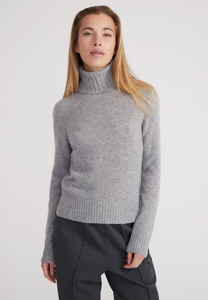 Pull à col roulé gris en tissu doux, doté de poignets et d'un ourlet côtelés, d'une coupe ajustée et d'une texture légère et confortable.