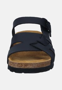 Black sandal with cork insole, featuring crossed synthetic straps and an adjustable buckle. Flat sole with a textured finish.